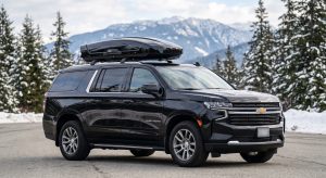 Black Chevrolet Suburban SUV rental equipped with an XL rooftop ski box for Whistler winter travel.
